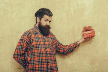 Frown bearded man with long beard holds red gift box