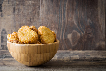 Fried chicken nuggets in bowl on wooden table

