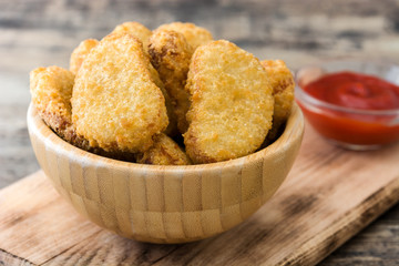 Fried chicken nuggets in bowl on wooden table
