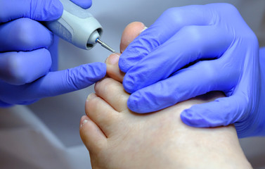 Pedicure specialist works with the patient in clinic
