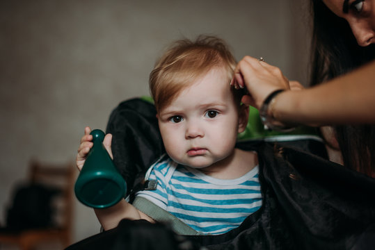 Serious 1-year infant boy during his first haircutting