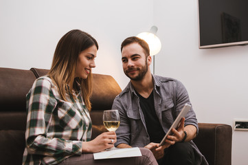 Young couple watching tablet and drinking wine at home