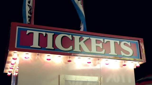 Sign advertising carnival tickets flashing at night.
