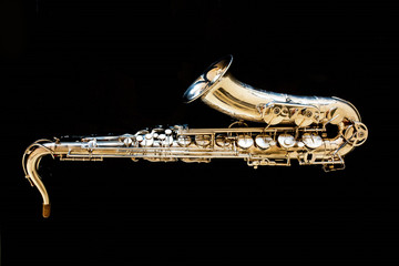 Saxophone tenor. Woodwind Classical Instrument. Jazz, blues, classics. Music. Saxophone on a black background. Black mirror surface. Music styles