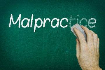 Hand erasing the word MALPRACTICE written on blackboard