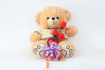 Brown teddy bear with a red rose and a gift box on a white background.