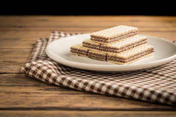 Cocoa wafers in white dish on wood table.