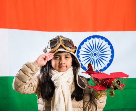 Happy Indian Or Asian Girl Kid Flying A Toy Metal Airplane Or Saluting Against Indian Flag Background - Kid And Flying For Country