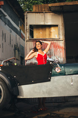 Beautiful girl in red dress in a car workshop