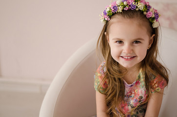 Little pretty girl is sitting in a studio, wearing floral dress and smile. Easter concept