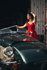 Fototapeta na wymiar Beautiful girl in red dress in a car workshop
