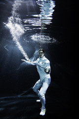 a male fencer fighting underwater with an epee