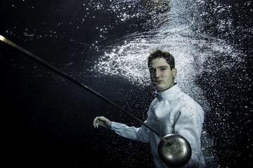 a male fencer fighting underwater with an epee