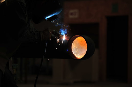 Arc Welder in helmet cutting pipe