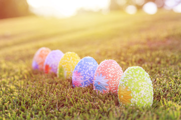 Color eggs on green grass with blur bokeh and sunlight background. For Easter day use