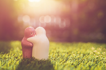 White and pink ceramic doll on green grass with blur bokeh and sunlight