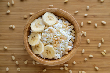 Healthy eating. Cottage cheese with banana and pine nuts.