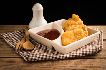 Chicken nuggets and sauce on wood table.