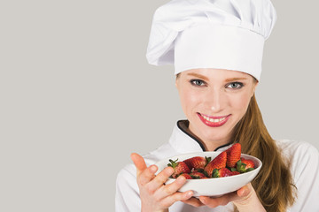 female chef smiling, holding a plate of strawberries