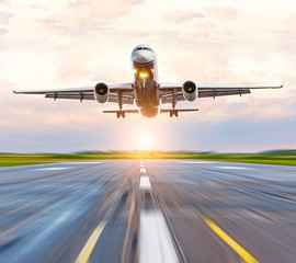 Airplane landing speed on the runway at the airport at sunset dawn