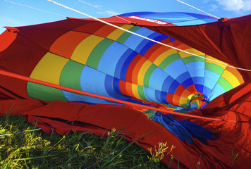 Launch of a red, blue, yellow balloon on the ground in a glade with grass in summer