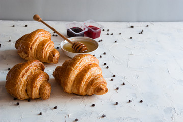 Croissant with honey and jam for breakfast. Chocolate crumbs.