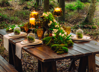 Wedding table decorations with candles, tulips and moss, in forest
