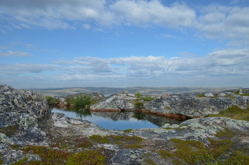 Fototapeta na wymiar Hills,tundra, and lake and clouds in the blue sky.