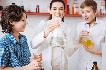 Nice cheerful woman holding a chemical flask
