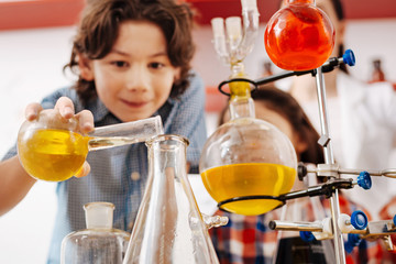Selective focus of chemical flasks being held by a boy
