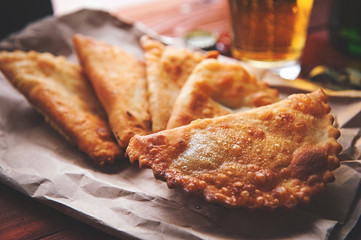 Chebureks with beer in rustic style on a wooden background. Pasties