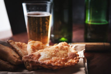 Chebureks with beer in rustic style on a wooden background. Pasties