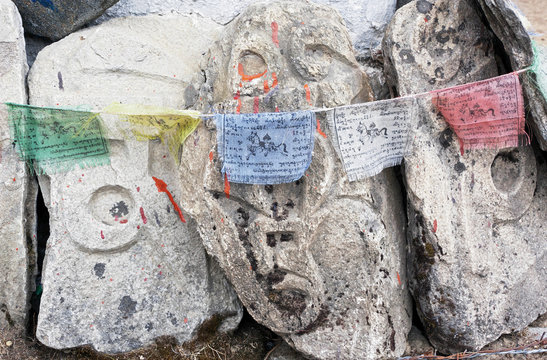 Fototapeta The stone along nepali trek on which a buddhist mantras and flags - Himalayas