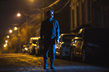 The man stand on the road. Evening night time. Telephoto lens shot