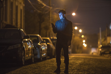 The man phone on the street. Evening night time. Telephoto lens shot