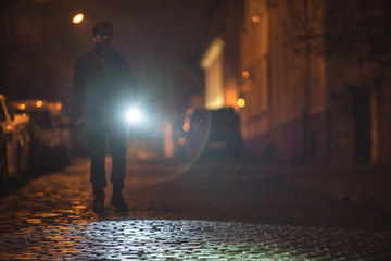 The man with a flashlight stand on the road. Evening night time - obrazy, fototapety, plakaty