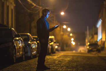 The man phone on the street. Evening night time. Telephoto lens shot