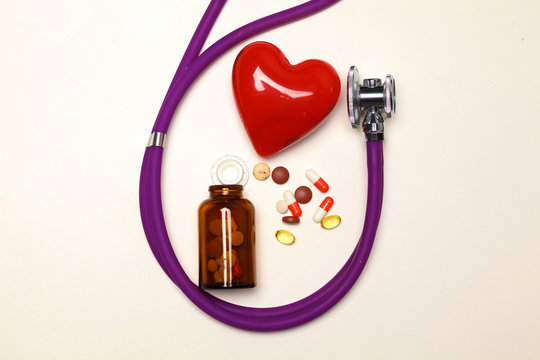 Stethoscope with pills and red heart isolated on white background