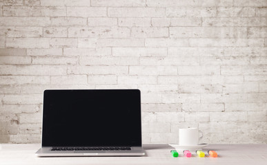 Fototapeta na wymiar Business laptop with white brick wall