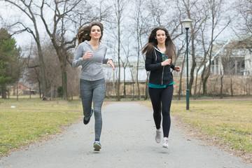 two young woman is running in a park