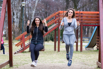 Obraz premium two young woman swinging in a park