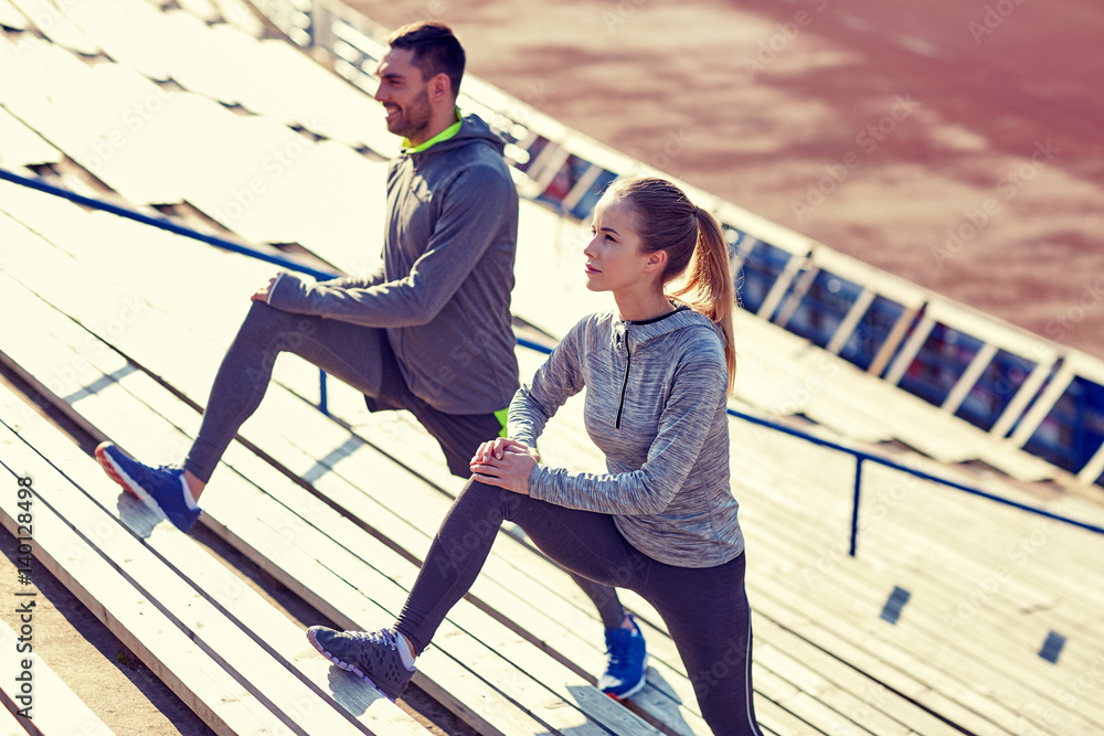 Poster couple stretching leg on stands of stadium