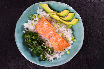 Salmon with spinach and avocado. Fish with rice and sesame seeds. View from above, top studio shot