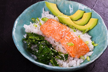 Salmon with spinach and avocado. Fish with rice and sesame seeds