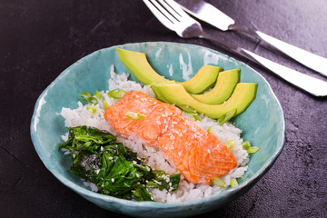 Salmon with spinach and avocado. Fish with rice and sesame seeds