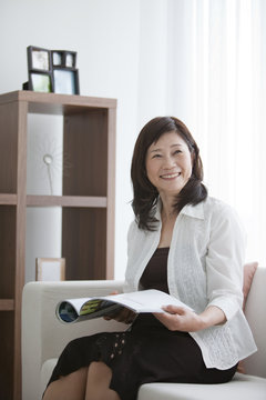 Mature Woman Reading A Magazine Drinking Tea