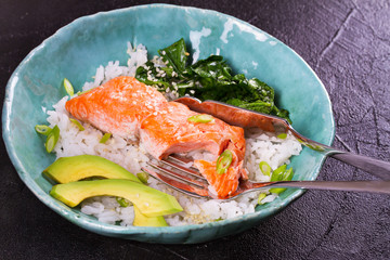 Salmon with spinach and avocado. Fish with rice and sesame seeds