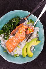 Salmon with spinach and avocado. Fish with rice and sesame seeds. View from above, top studio shot
