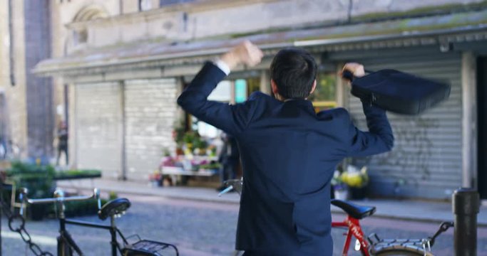 A businessman dancing in the square and is glad to have received a promotion or winning a bet. Concept: finance, business, elation, victory, wager, career, dance