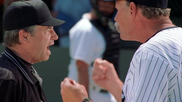 Close-up profiles of a coach and an umpire having an altercation